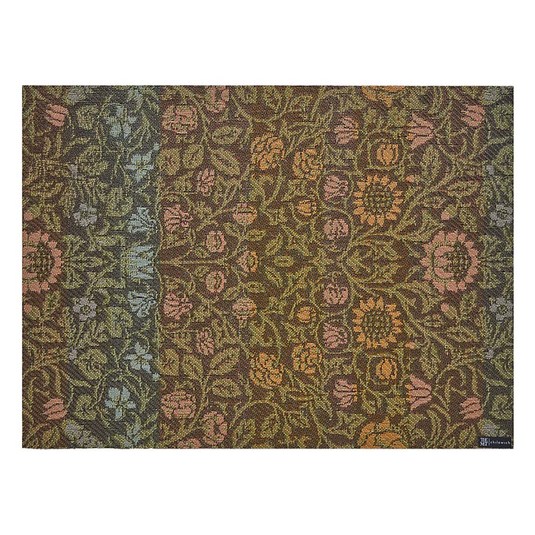 A woven placemat with a floral design in brown, green, and pink colors, featuring a small label in the bottom right corner.