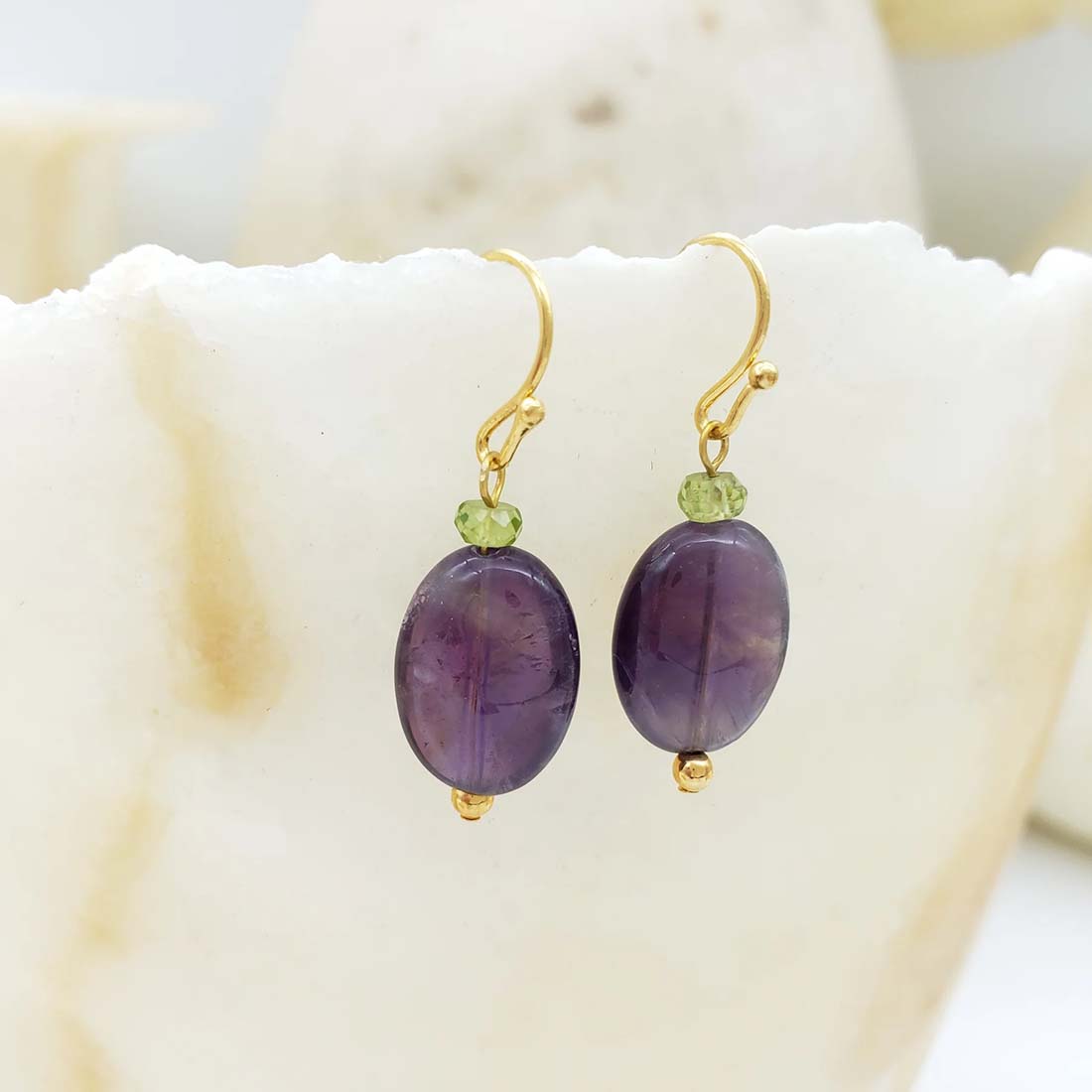 Purple beaded earrings with gold hooks on a white background