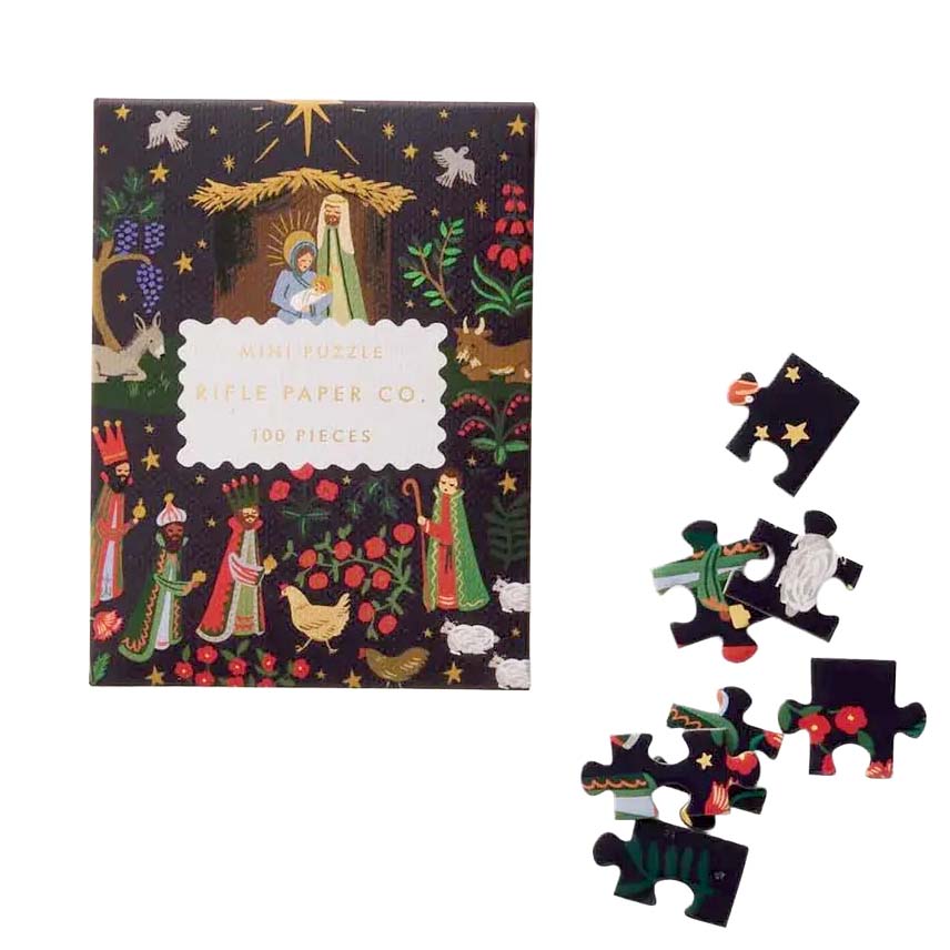 Jigsaw puzzle packaging with nativity scene design and scattered pieces on a white background