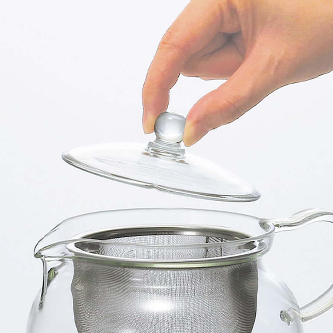 Clear glass teapot with a metal filter on a white background