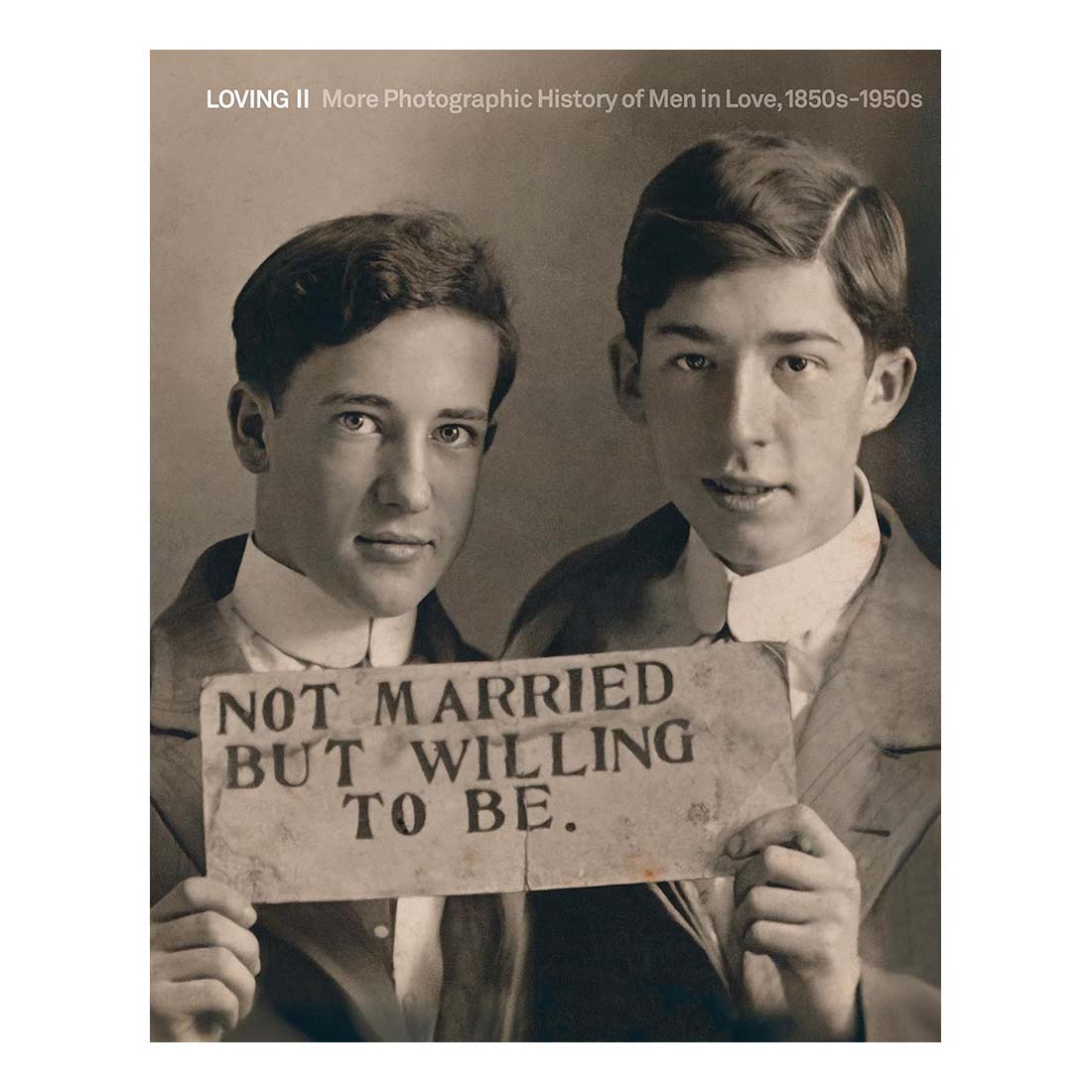 Vintage-style photo of two men holding a sign that reads 'Not Married But Willing To Be.'