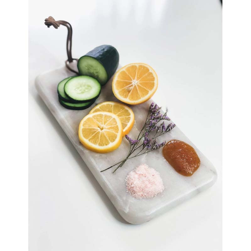 Rectangular marble cutting board with a gold handle on a white background