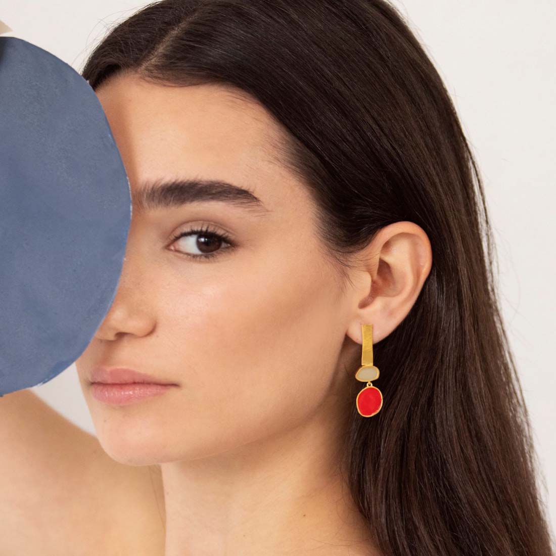 Gold and red earrings on a white background