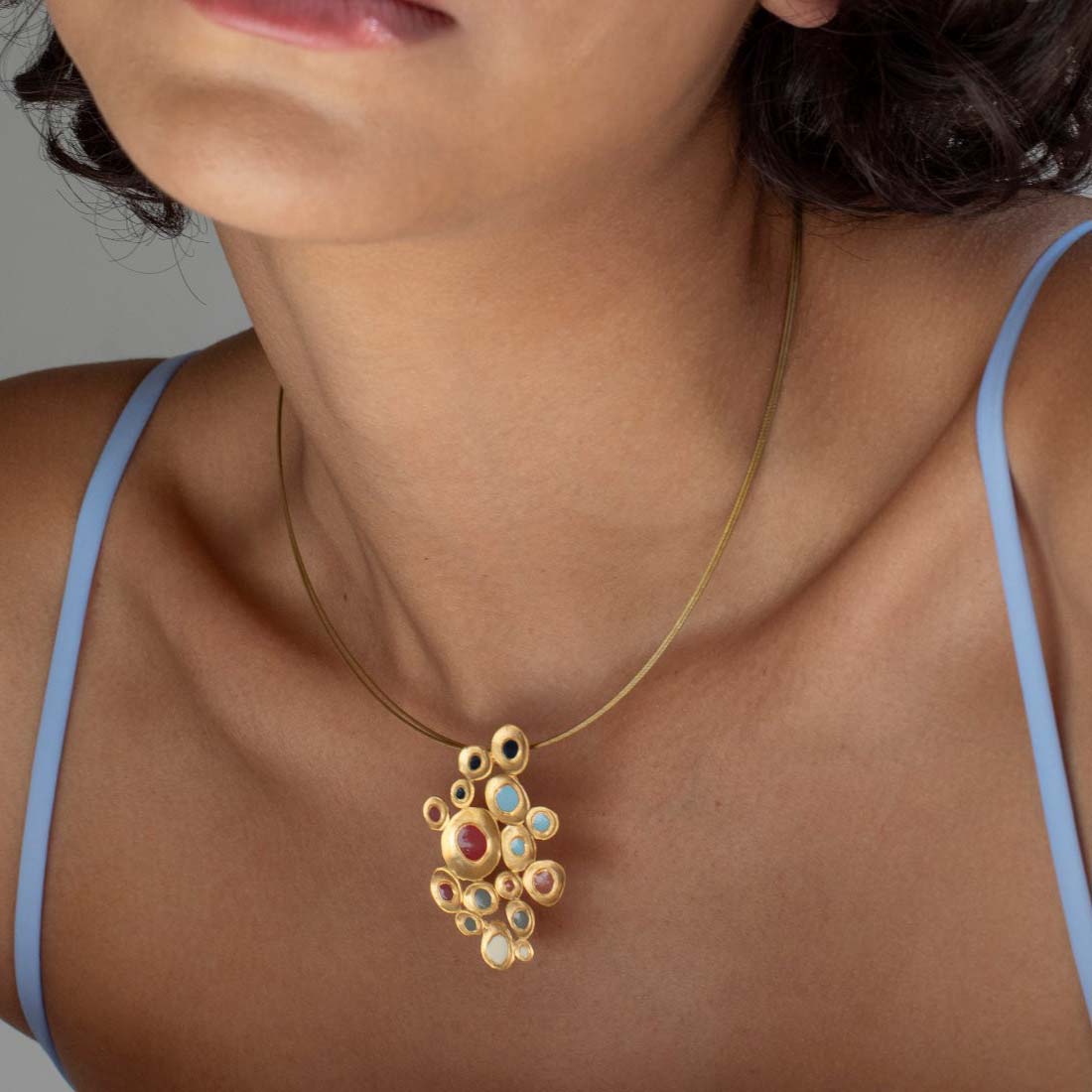Gold necklace with a colorful pendant on a white background