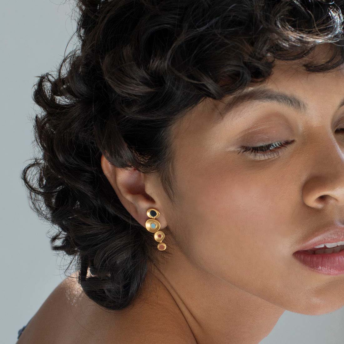 Gold earrings with multicolored stones on a white background