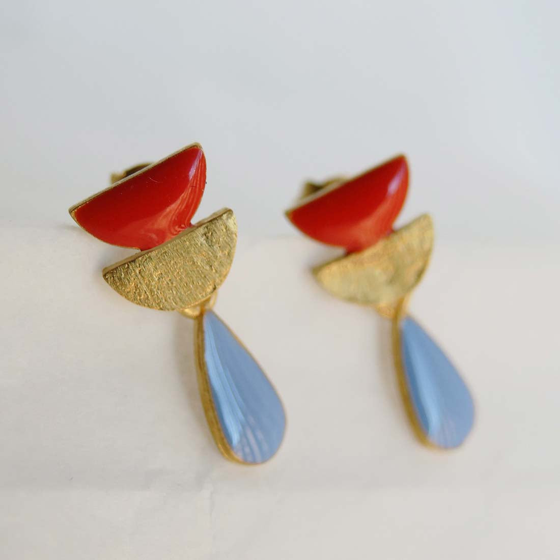 Pair of earrings with red, gold, and blue colors on a white background