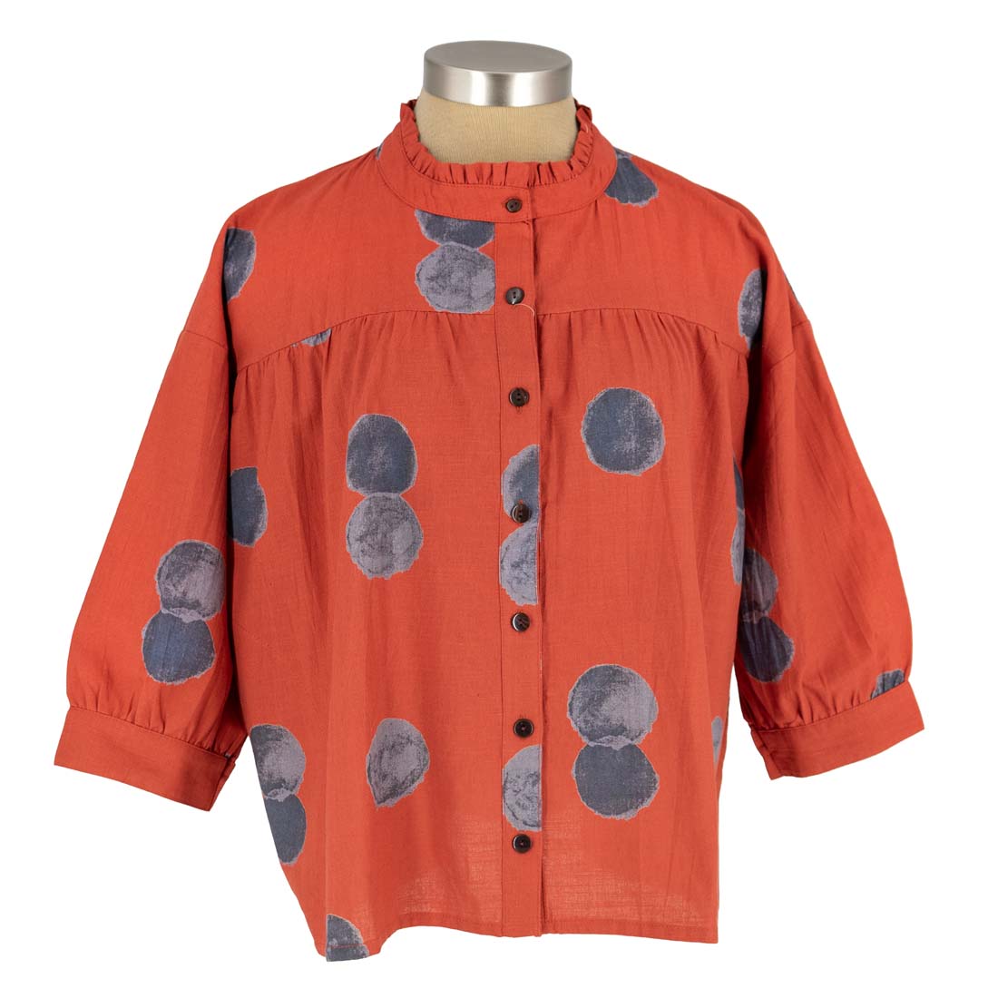 Red shirt with gray circular patterns on a mannequin against a white background