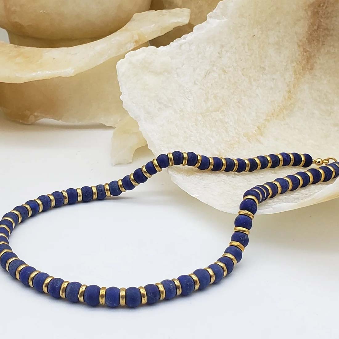 Necklace with blue beads and gold accents on a white background