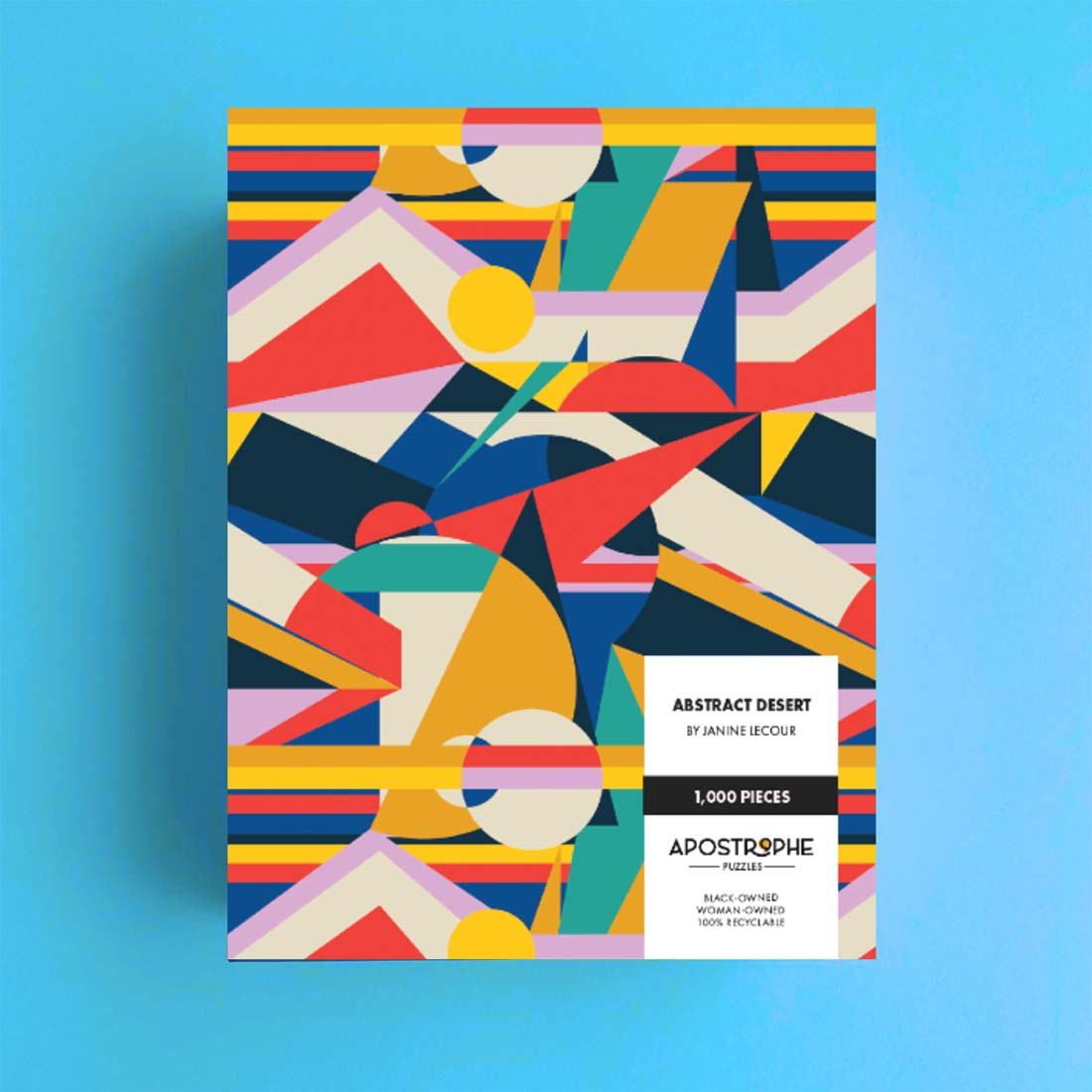 A packaged jigsaw puzzle with a vibrant, geometric abstract design featuring bold colors, titled 'Abstract Desert' by Janine Lecour.