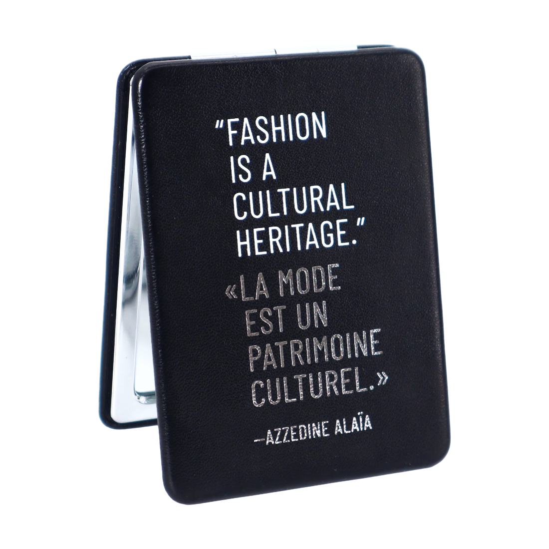 A black rectangular compact-style case with a mirrored inner panel visible on the left side, featuring a white printed quote about fashion and cultural heritage, including the name Azzedine Alaata.