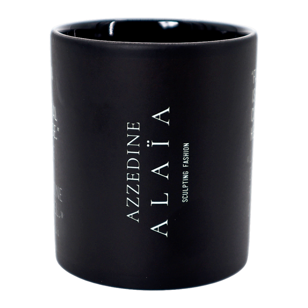 A matte black ceramic mug with a white printed quote by Azzedine Alaéa on the side, shown against a plain white background.