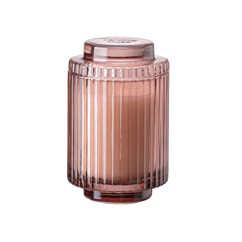 A ribbed glass candle in a pink hue with a white candle visible from the top
