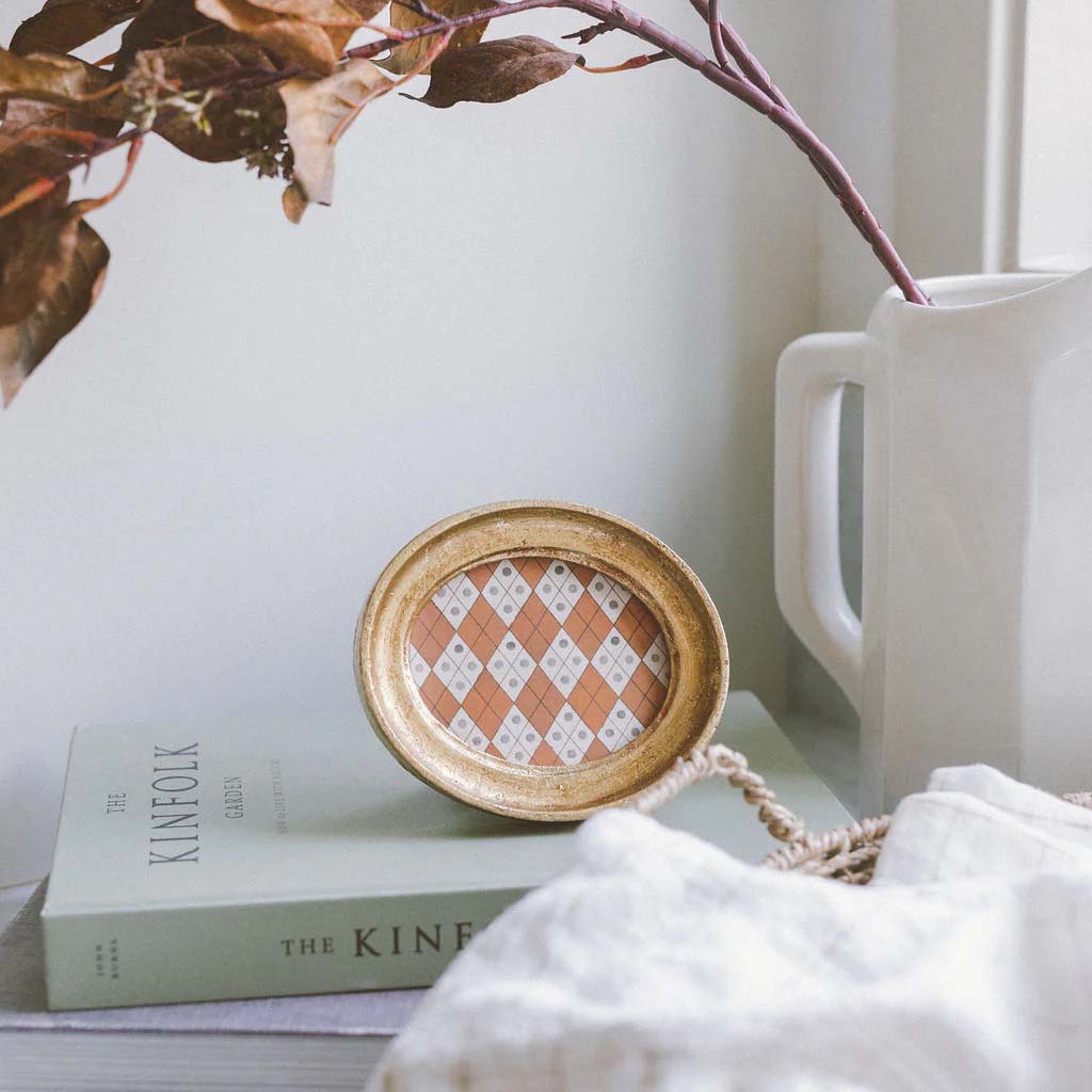 Decorative plate with a checkered pattern inside a gold frame on a white background