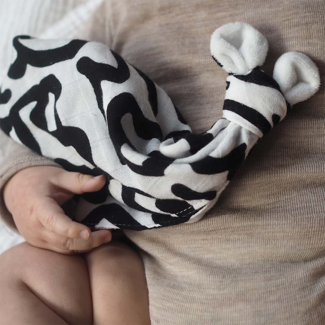 A black and white security blanket with a geometric pattern, featuring plush ears.