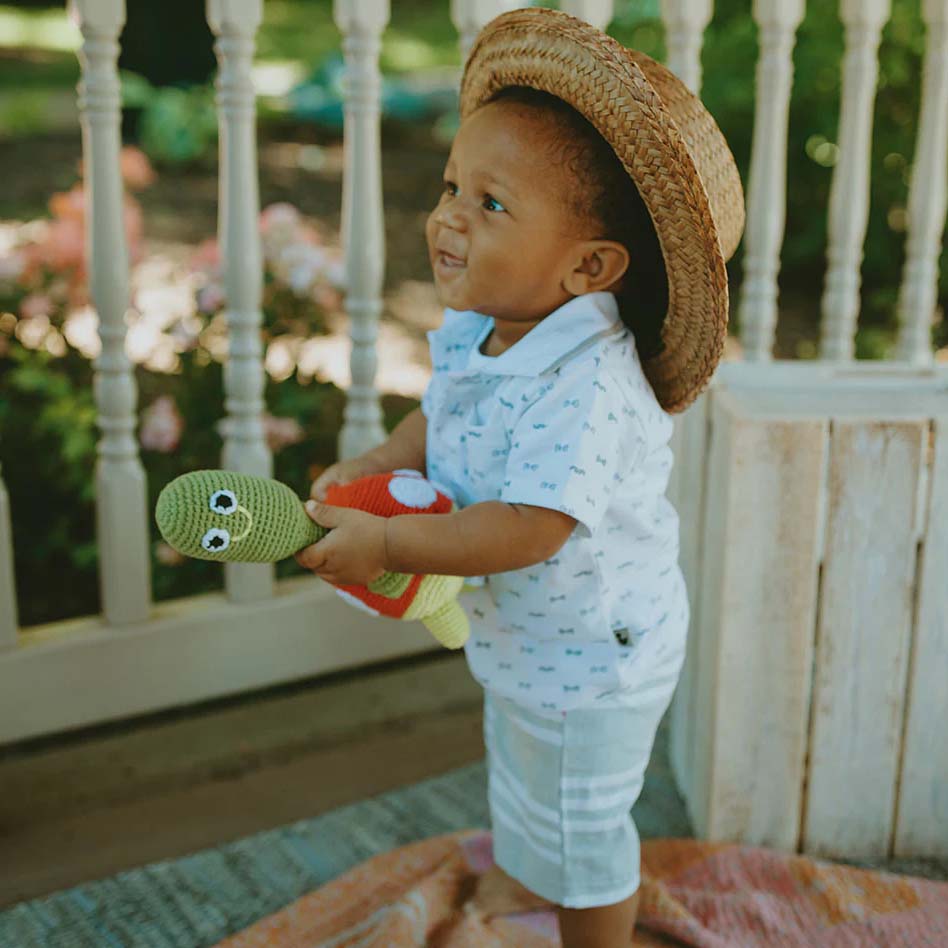 Crocheted turtle toy with a red shell on a white background
