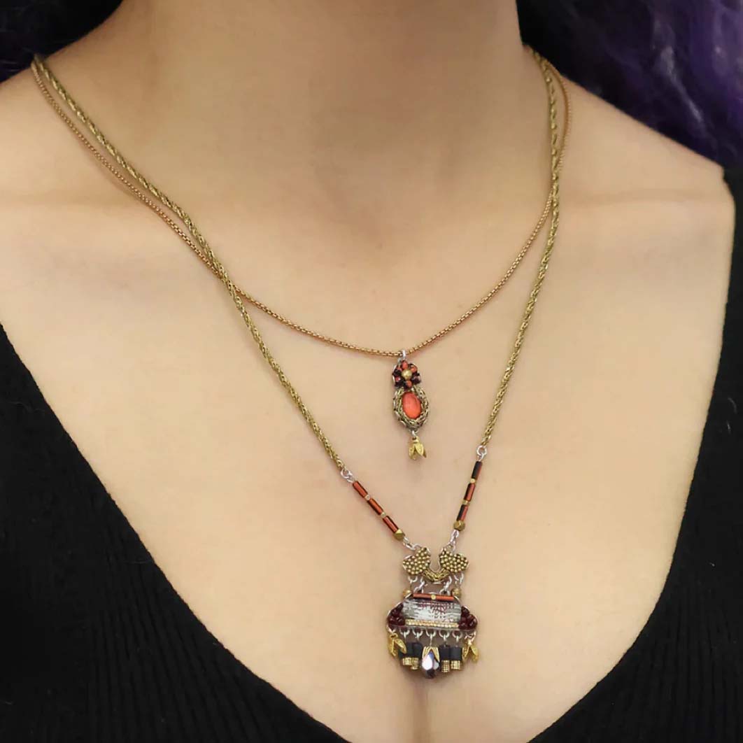 Necklace with decorative pendant on a person wearing a black top