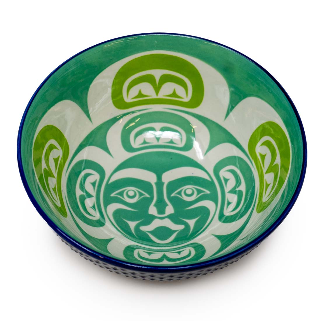 A medium-sized porcelain bowl with a contemporary Indigenous design in green and white colors, with a blue rim.