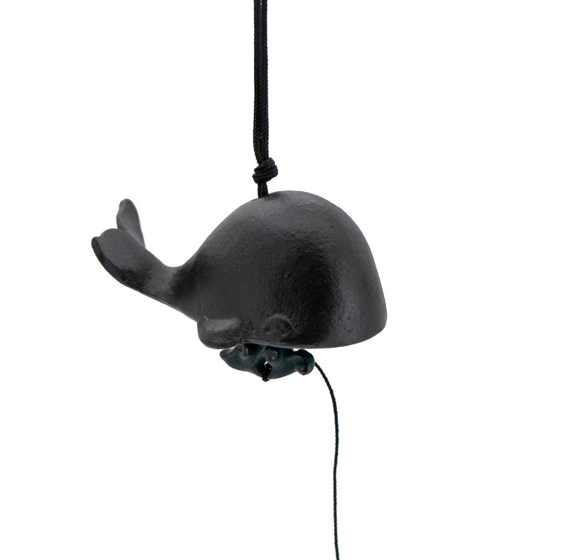 A black cast iron wind chime shaped like a whale, with visible suspension loop and mallet.