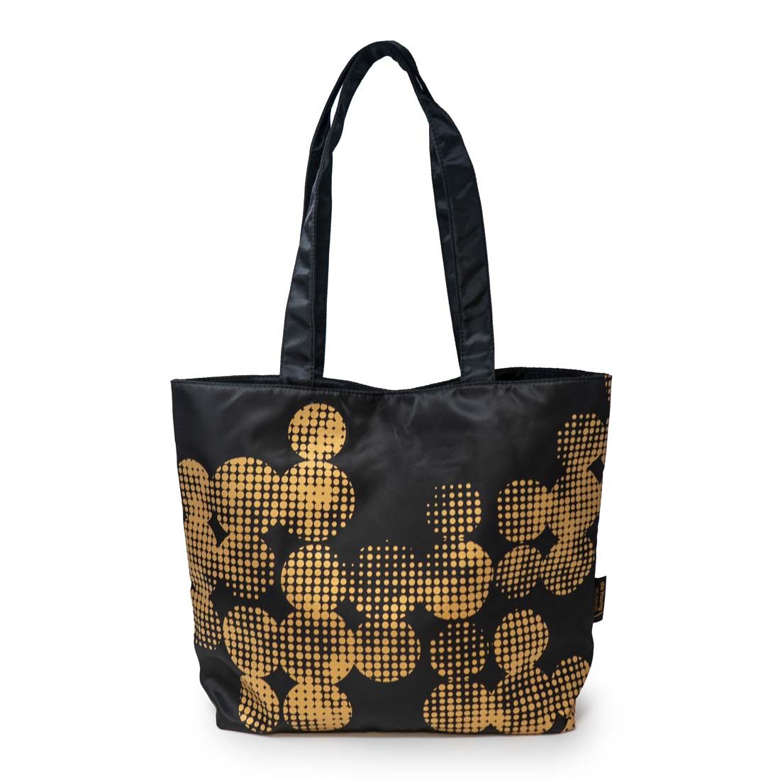 A black tote bag with a geometric pattern of golden dots, inspired by the de Young museum's copper façade.