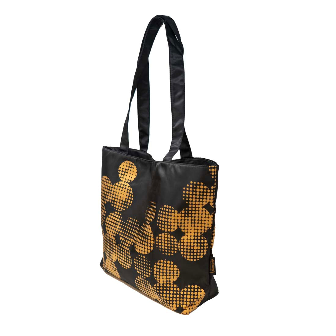 A black tote bag with a geometric pattern of golden dots, inspired by the de Young museum's copper façade.