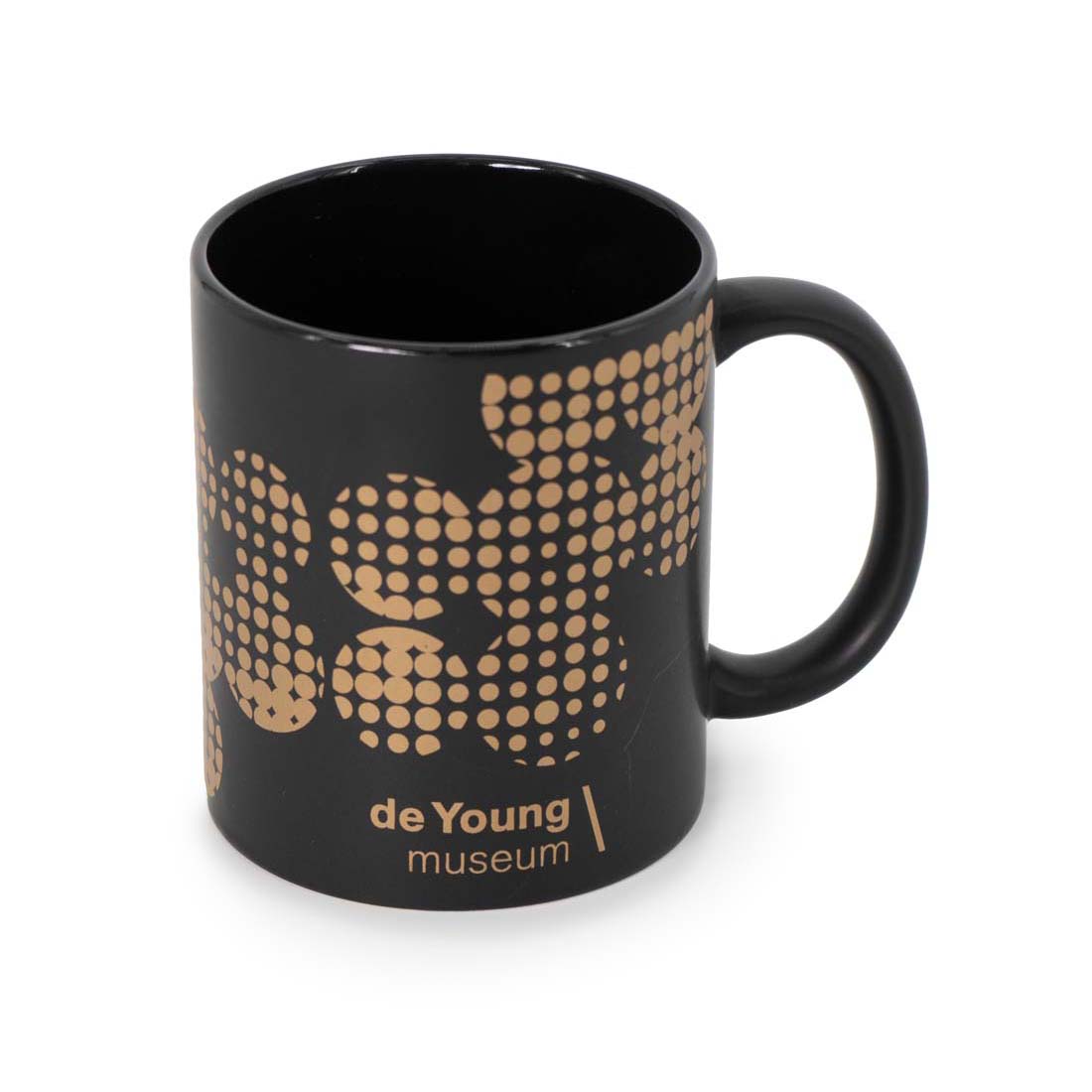 A black matte ceramic mug with metallic copper dot detail and the text 'de Young museum' printed on the side.