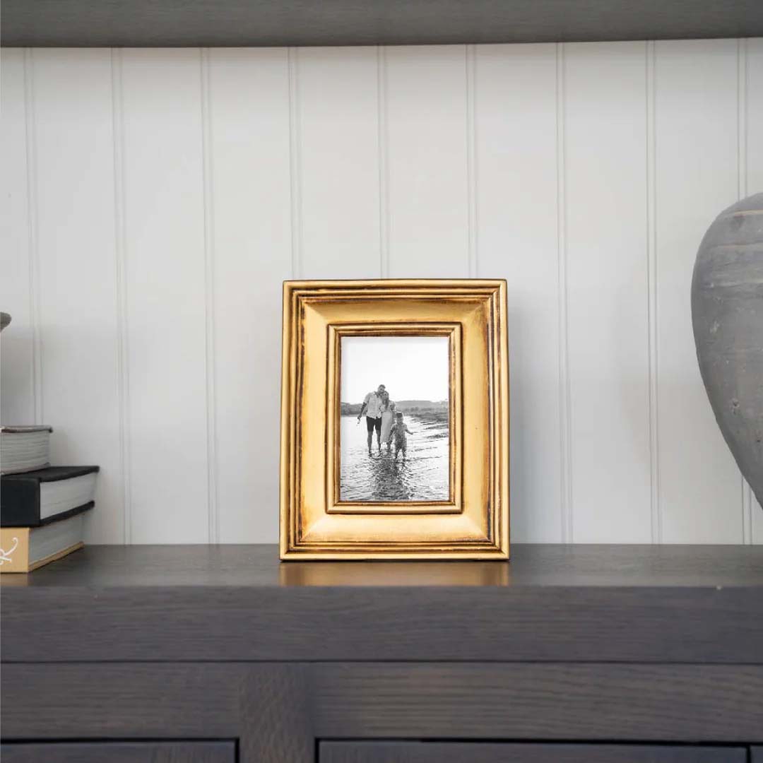 Gold picture frame with floral fabric inside on a white background