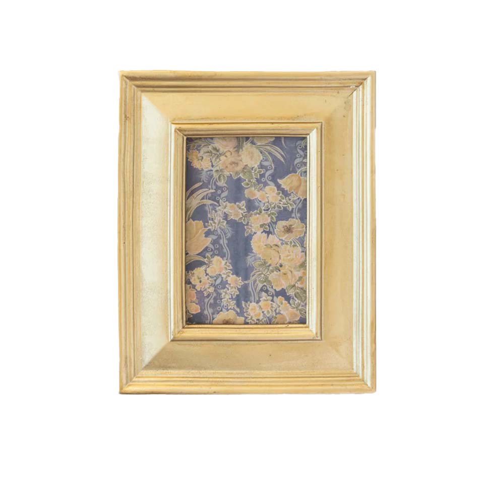 Gold picture frame with floral fabric inside on a white background