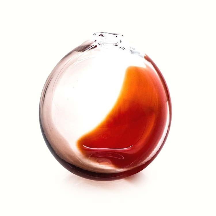 Glass ornament with a red and brown design on a white background