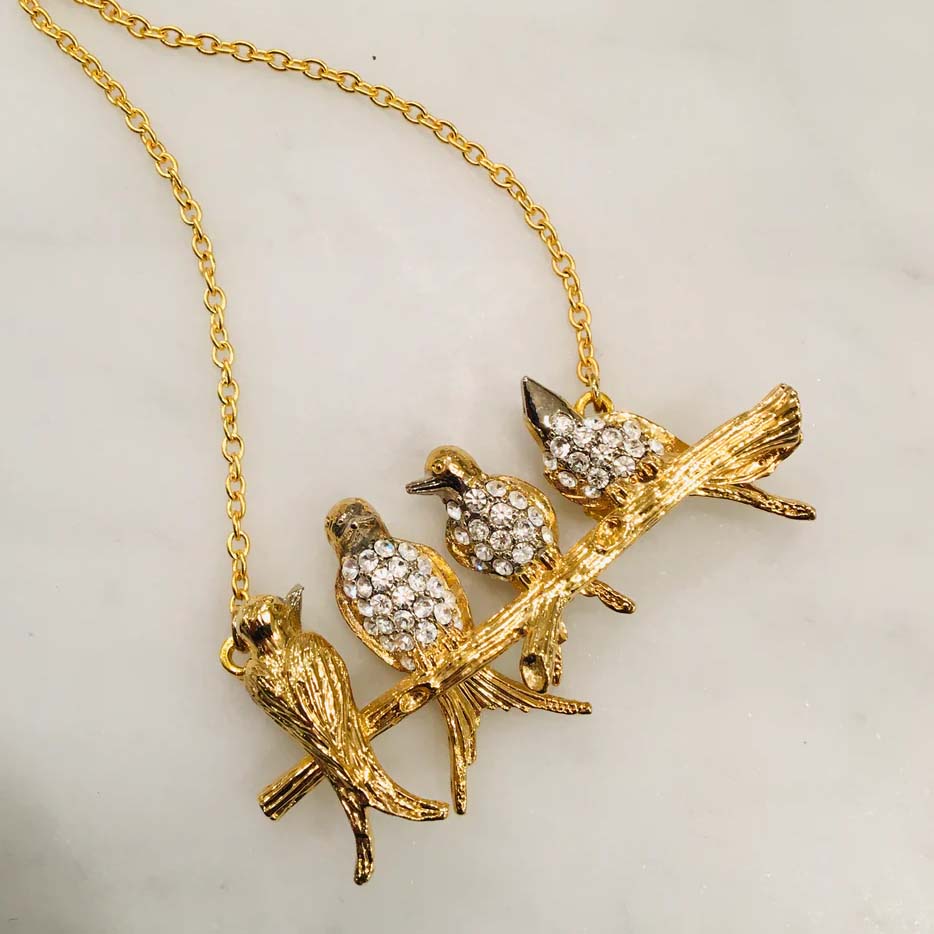 Gold necklace with bird-shaped pendant on a white background