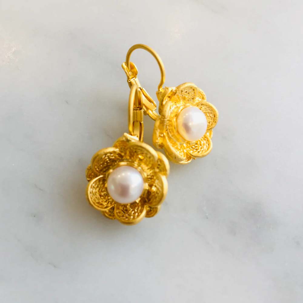 Gold earrings with pearl centers on a white background