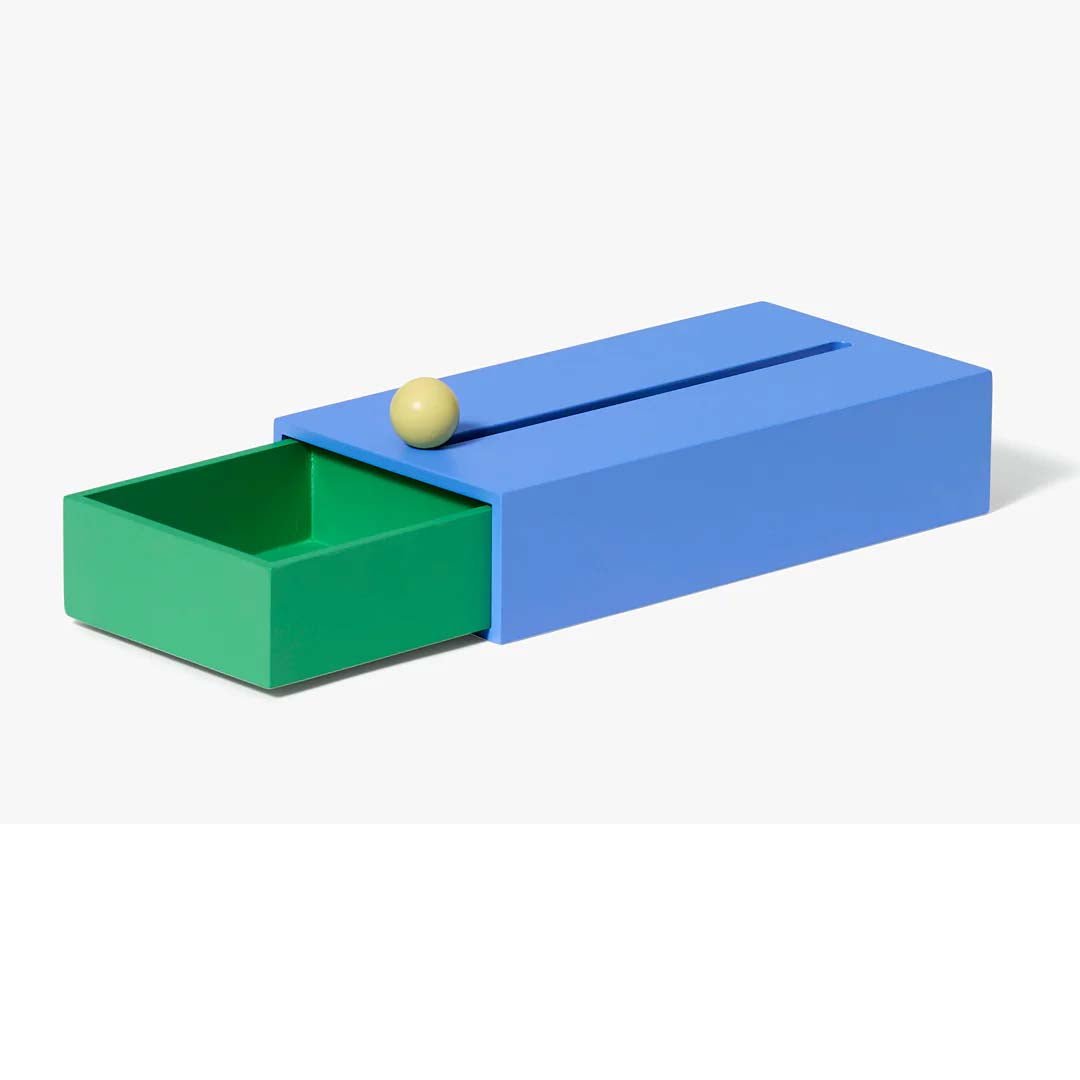 A large blue and green geometric storage box with a slot on top and a knob on the front drawer, set against a white background.