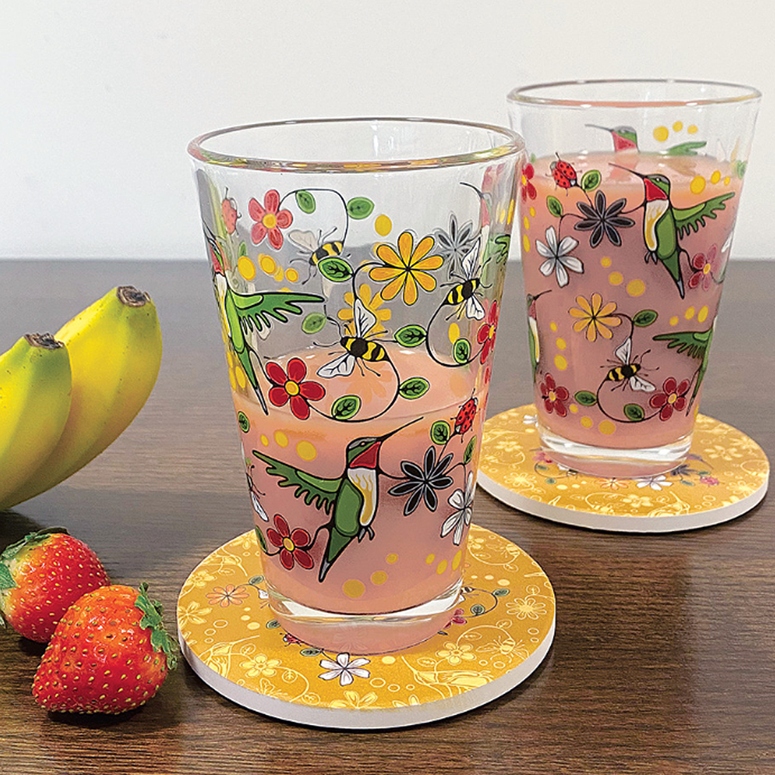 Two glass tumblers with colorful animal and floral designs on a white background