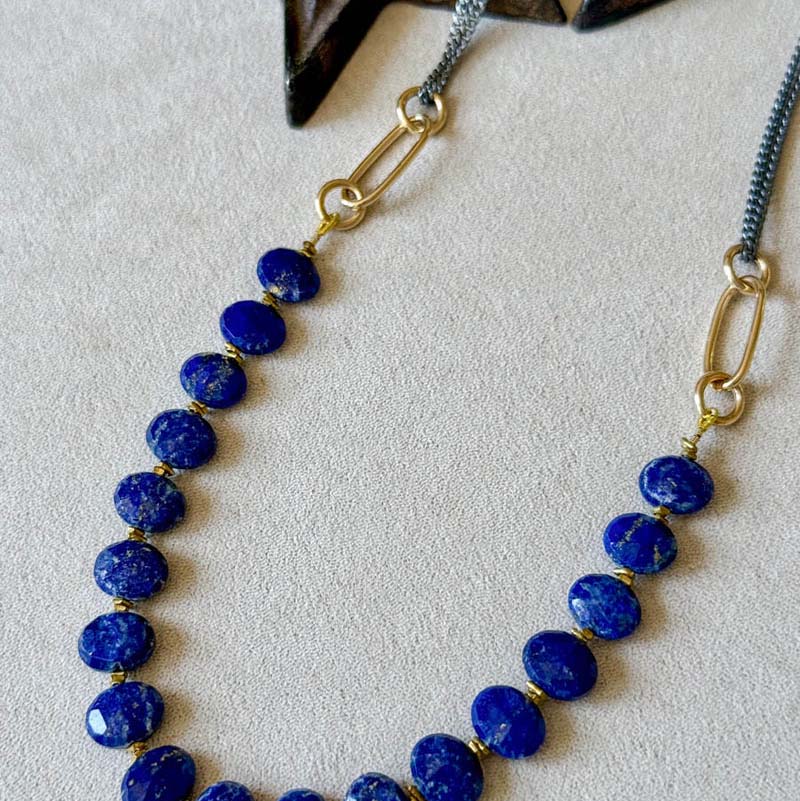 Necklace with blue beads and gold accents on a white background