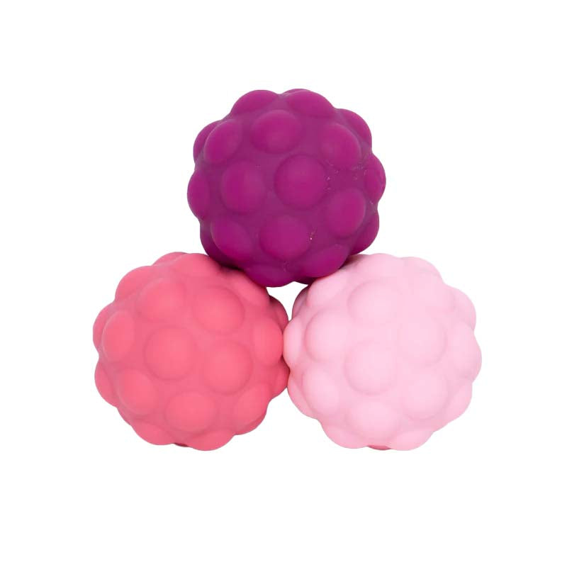 Three textured silicone balls in pink, red, and purple on a white background