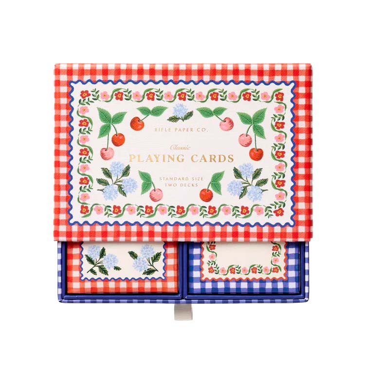 Playing cards with cherry and floral design on a red and white checkered background