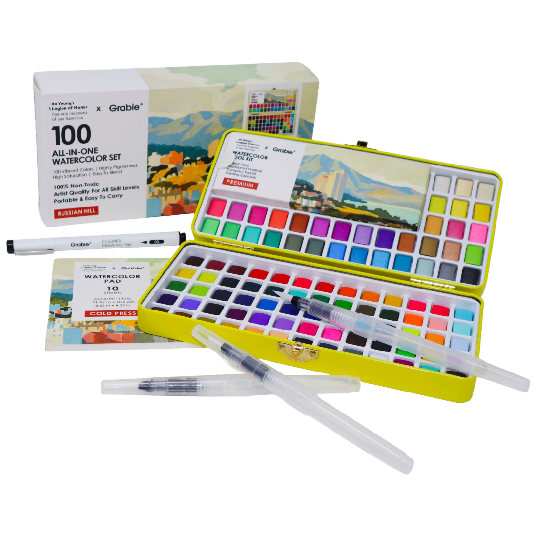 A Grable 100 All-In-One Watercolor Set shown open, with a yellow metal case filled with many watercolor pans, two clear water brushes, a pen, the product box, and a booklet on a clean white background.