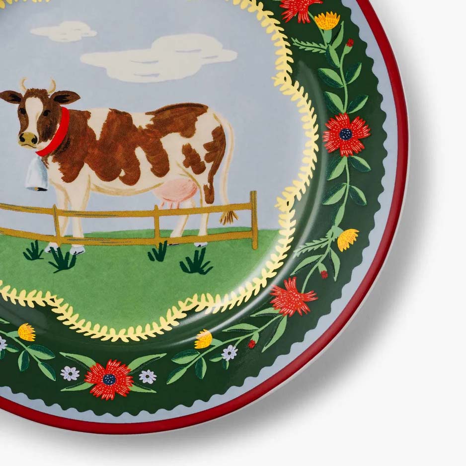 Decorative plate with a cow illustration and floral design on a white background