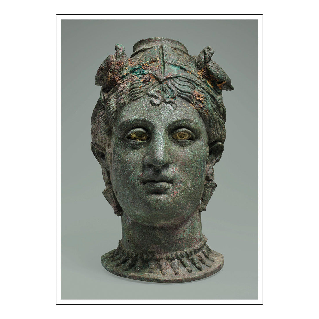 Bronze head of a classical figure with detailed hair and facial features on a gray background