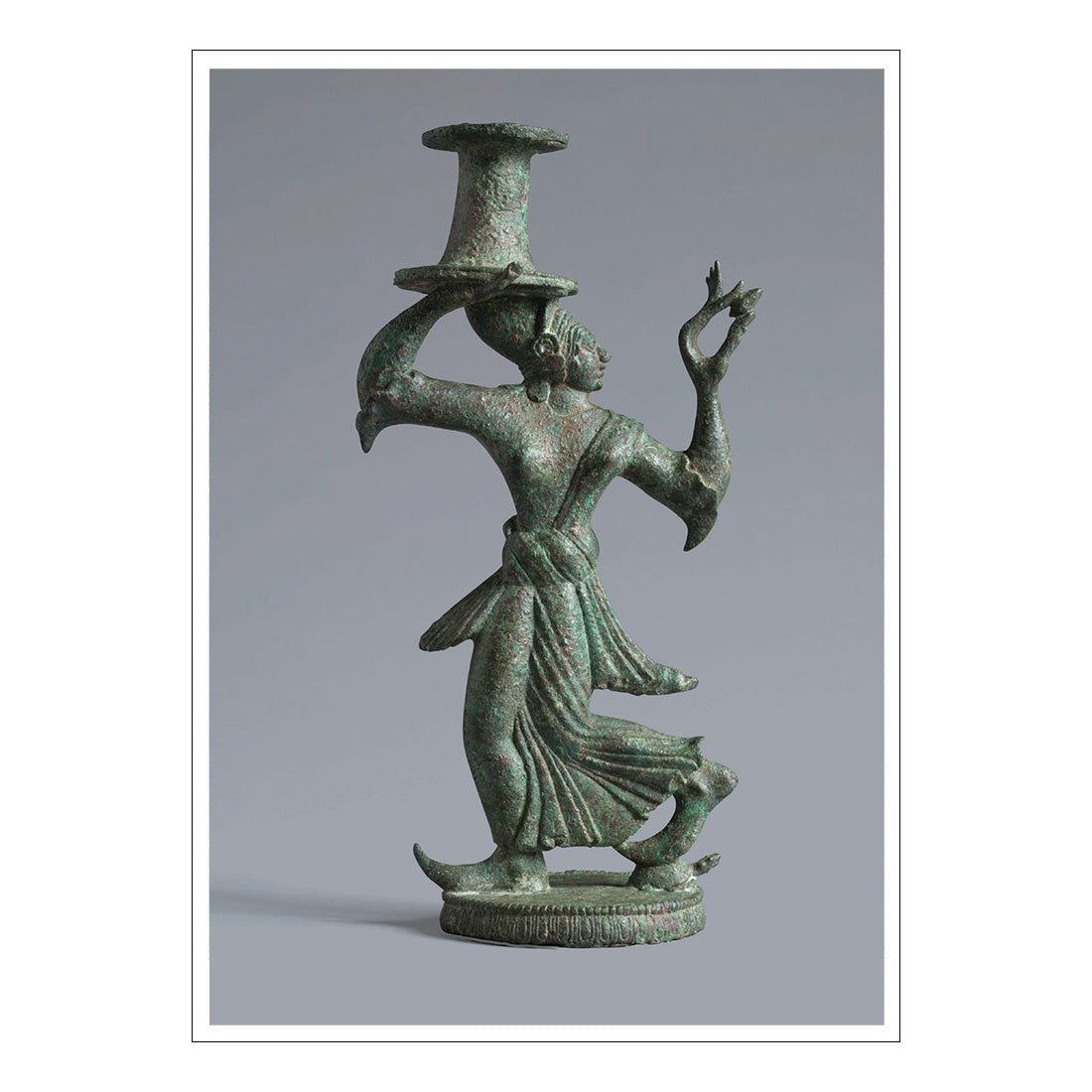 Bronze statue of a dancer with a candle holder on a gray background