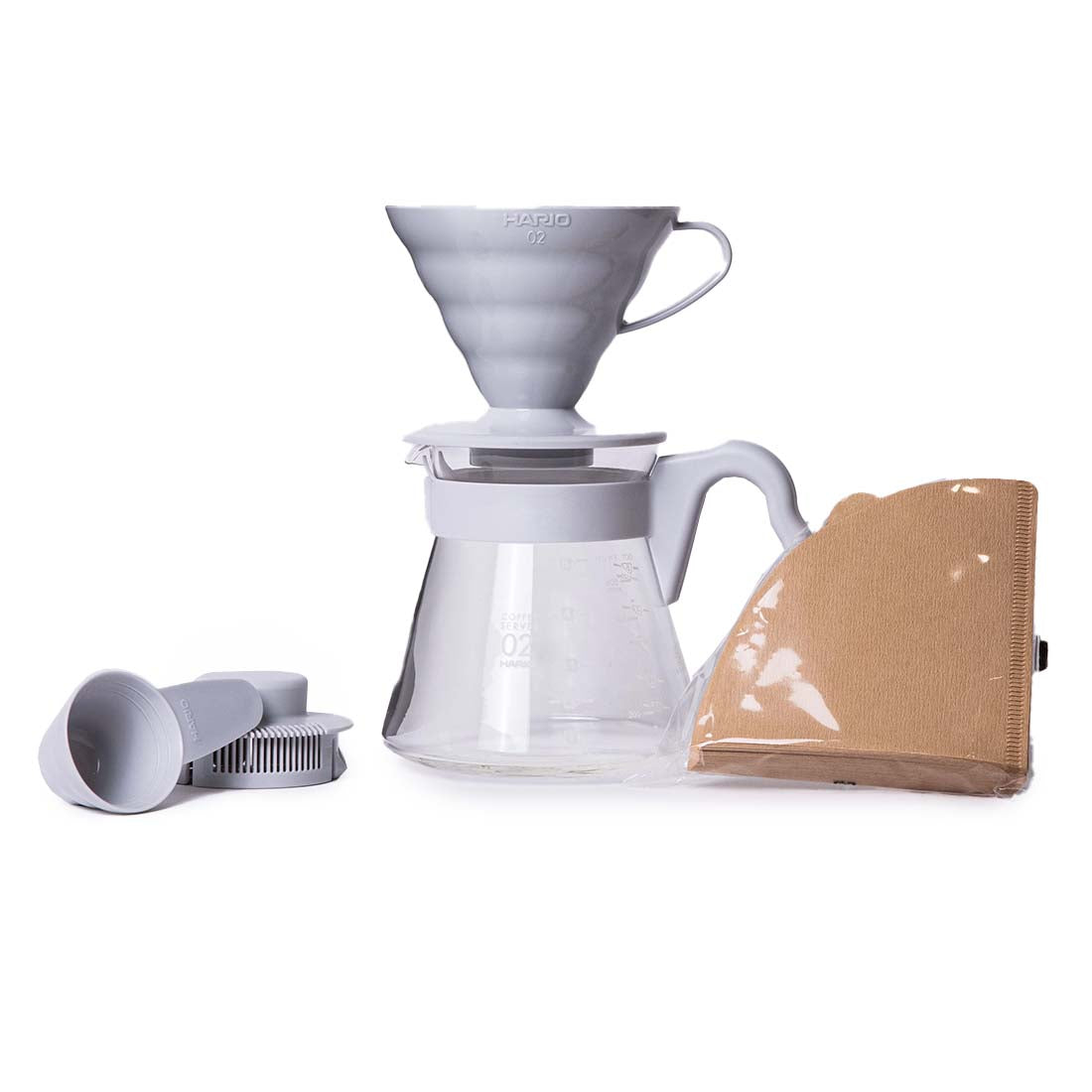 Coffee brewing set with glass carafe, filter, and brown coffee bag on a white background