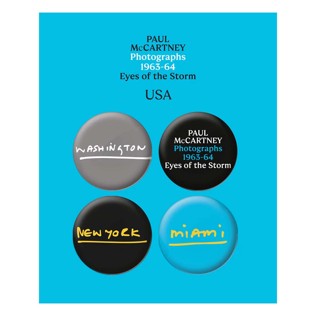 A set of four round pins with different colors and text related to the Paul McCartney Photographs 1963-64: Eyes of the Storm exhibition. Cities mentioned are Washington, New York, Miami, and the text 'Paul McCartney Photographs'.