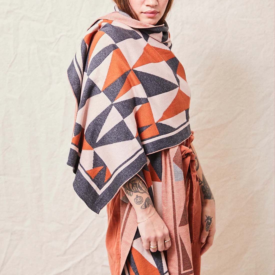 A geometric patterned wrap in cinnamon, charcoal, and white colors, draped and knotted at the ends.