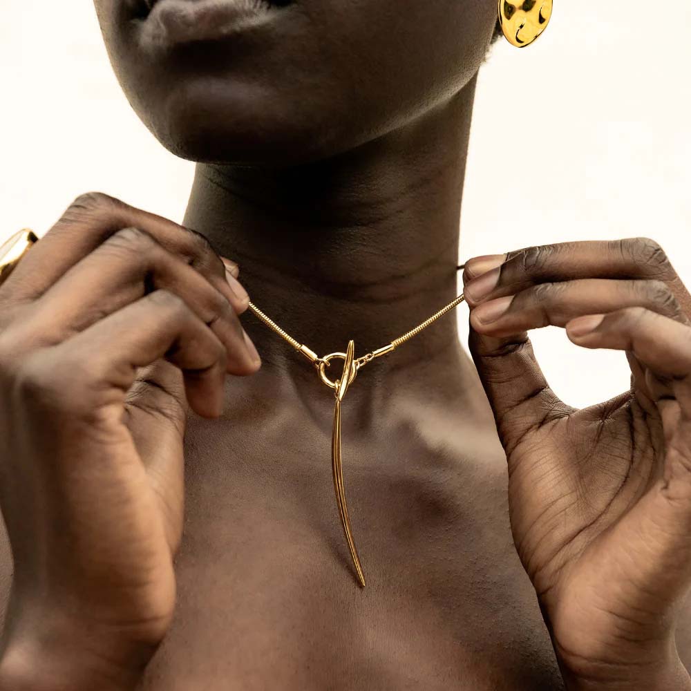 Gold necklace with a unique pendant on a white background