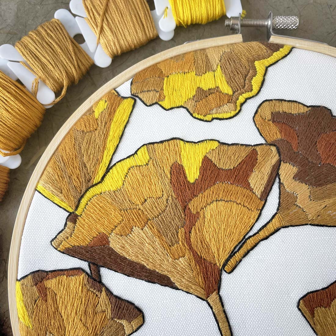 Embroidery hoop with yellow and brown leaf pattern on a white background