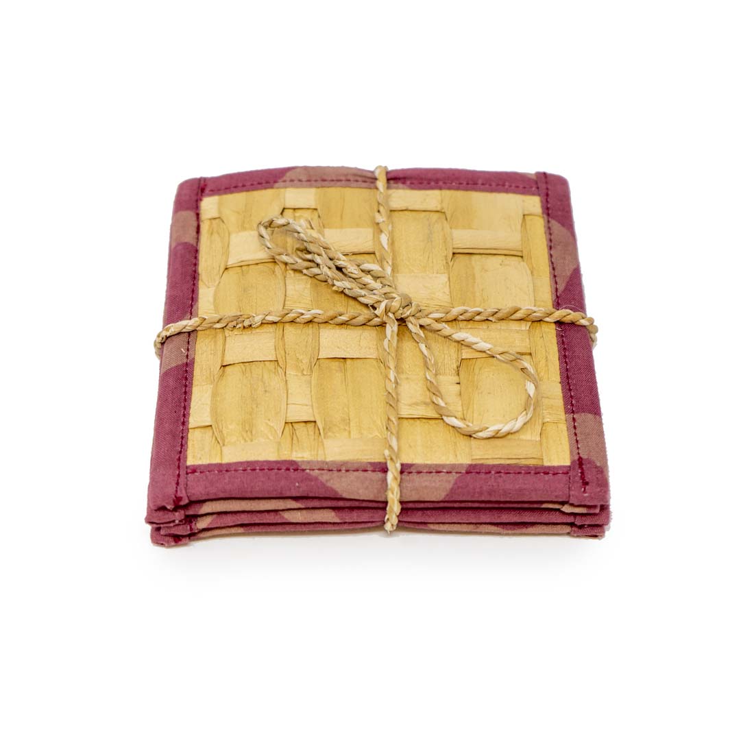 A set of four square coasters made of water hyacinth, with a geometric pattern and red batik edging, tied together with a string.