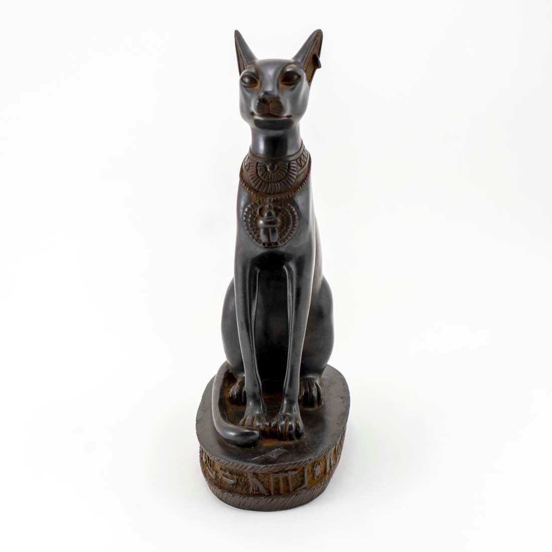 A statue of the ancient Egyptian cat goddess Bastet, seated with a hieroglyphic collar, on a decorative base.